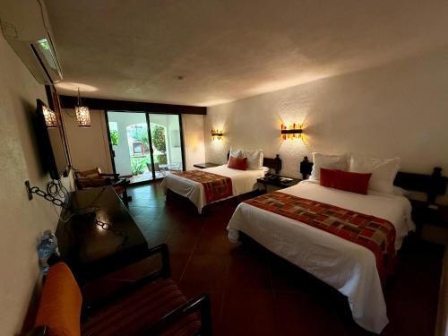a hotel room with two beds and a television at Hotel Hacienda Taboada (Aguas Termales) in San Miguel de Allende