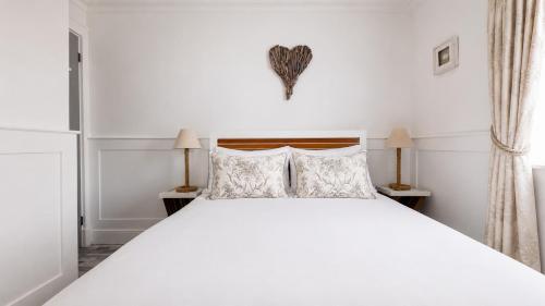 a bedroom with a large white bed with two lamps at Melbourne Place Apartment in Port Bannatyne