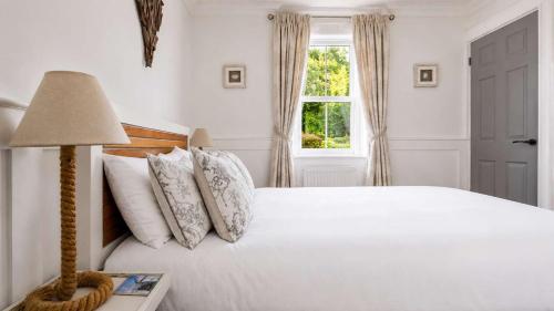 a bedroom with a white bed with a lamp and a window at Melbourne Place Apartment in Port Bannatyne