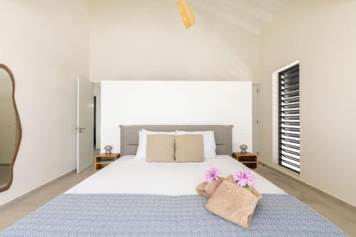 a white bedroom with a large bed with two pillows at Villa Dushi Brisa 650 - Coral Estate in Willibrordus