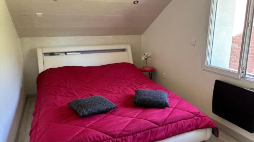 a bedroom with a pink bed with two pillows on it at Maison charmante en bordure de la Creuse in Glénic
