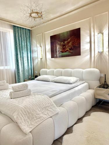 a white bedroom with two beds and a couch at Louise Luxury - free parking in Nyíregyháza
