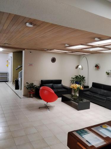 a living room with a couch and a red chair at Apartamentos Percales in Bogotá