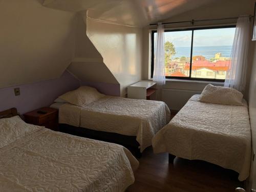 a hotel room with two beds and a window at Altos de Miramar in Puerto Montt