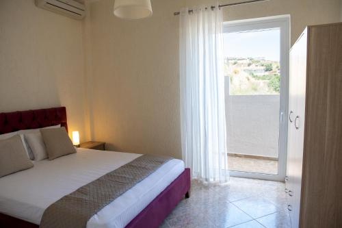 a bedroom with a bed and a door to a balcony at Oasis Resort Pure Relaxation Serenity in Agia Marina Mikrolimanou