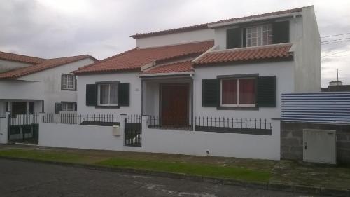 une maison blanche avec des toits rouges et une clôture dans l'établissement Pedro Sousa Rooms na Relva, à Ponta Delgada