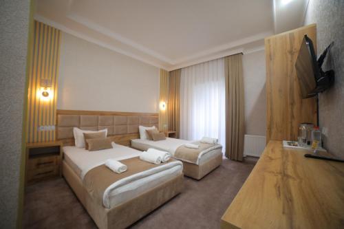 a hotel room with two beds and a flat screen tv at Tinchlik Plaza in Urganch