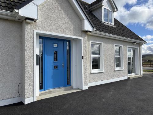 a house with a blue door on a driveway at Beach House in Donegal