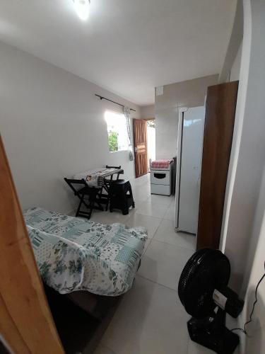 a room with two beds and a kitchen with a refrigerator at Kitnet Perequê in Matinhos