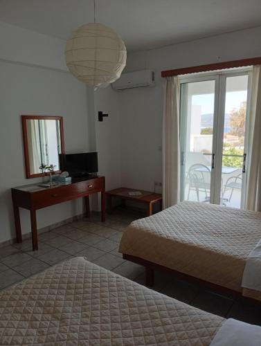 a bedroom with two beds and a desk and a mirror at Gikas Apartments Triple Studio Garden View A2 in Marmari