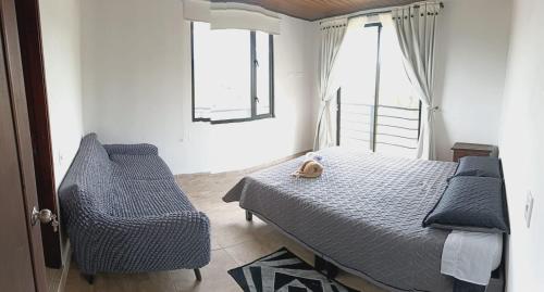 a bedroom with a bed and a chair and two windows at El Eden in Sáchica
