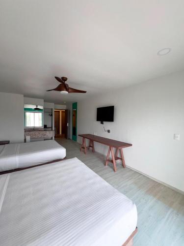a room with two beds and a ceiling fan at Hotel Tuki Tulum in Tulum
