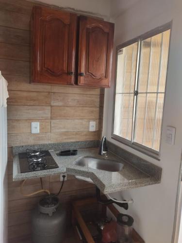 a small kitchen with a sink and a stove at Estúdio moderno com cozinha america in Ilhéus