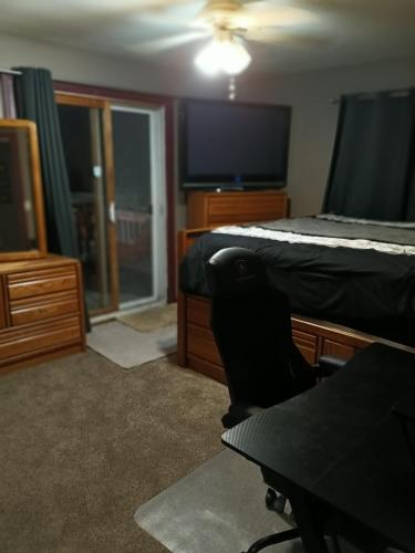a bedroom with a bed and a chair and a tv at Private room in Omaha