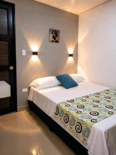a bedroom with a bed and two lights on the wall at Hostal Caiman Del Rio in Barranquilla