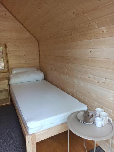 a bed in a wooden room with a table at Happy House Hel in Hel