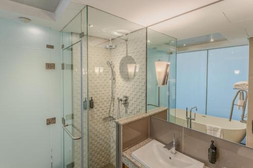 a bathroom with a glass shower and a sink at Royal Continental Hotel in Dubai
