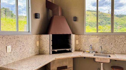 a kitchen with a stove and a sink and two windows at O Recanto Pousada in Serra Negra