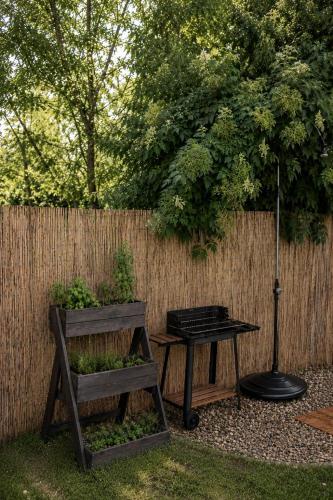 a table and a bench next to a fence at Árnyaskert Vendégház in Békésszentandrás