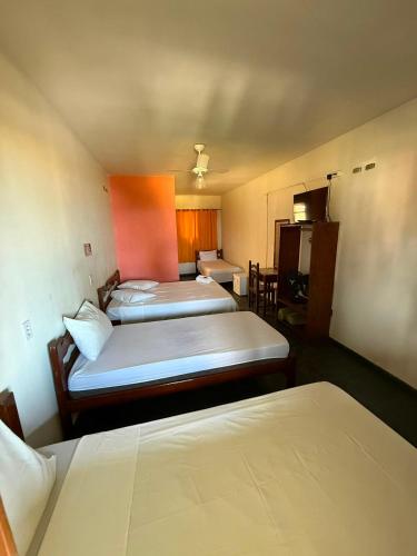 a hotel room with three beds and a kitchen at Pousada Cantinho do Mar - pé na areia in Guarujá