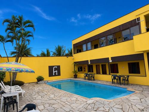 a hotel with a swimming pool and a yellow building at Pousada Cantinho do Mar - pé na areia in Guarujá
