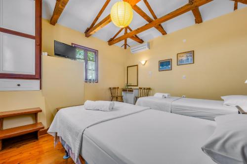 a room with two beds and a tv at Aiolos Rooms in Tsoukalades