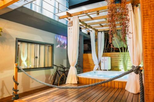 a bath tub in a room with a bike at The Beach House Estadias in Itapoa