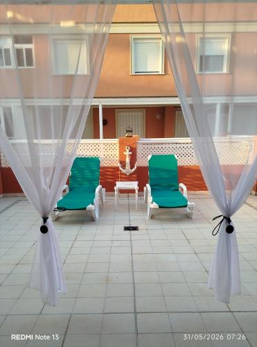 two green chairs and a table on a patio at Apartamento Perea playa in Tavernes de Valldigna