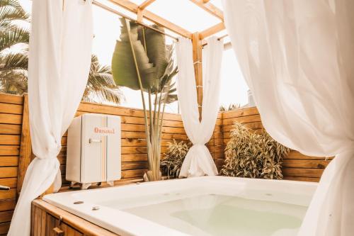 a bath tub in a room with a window at The Beach House Estadias in Itapoa