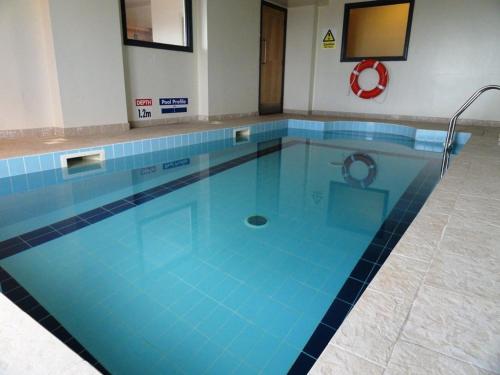 a large swimming pool with blue tiles on the floor at Stunning Two Bed Sea View Apartment with Pool & Gym in Newquay