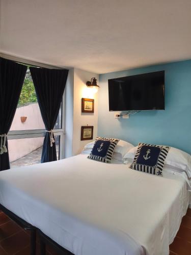 a bedroom with a large white bed with a flat screen tv at Casetta Mami in Camogli