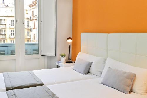 1 dormitorio con 2 camas blancas y ventana en Apartamentos Calle Larios, en Málaga