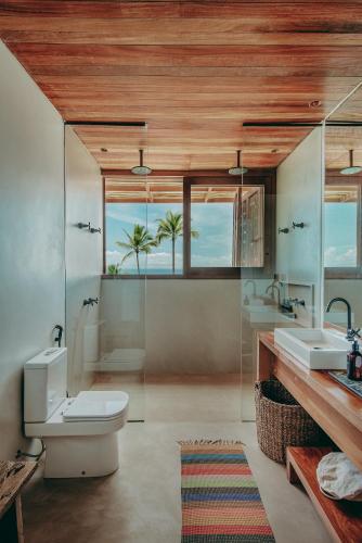 a bathroom with a toilet and two sinks at Barracuda Hotel & Villas in Itacaré