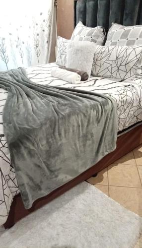 a bed with a gray blanket on top of it at Soshanguve Lux Accom Room 03 in Soshanguve