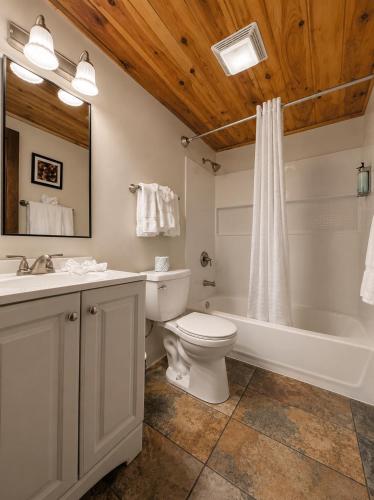 a bathroom with a toilet and a tub and a sink at Depe Dene Lakeside Resort in Lake George