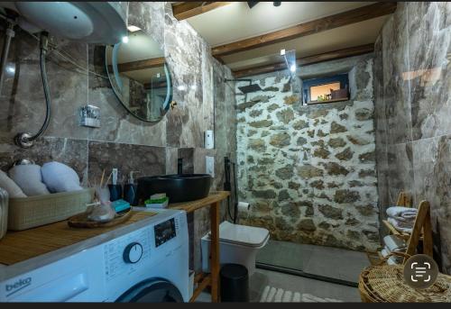 a bathroom with a washing machine and a stone wall at The Stonehouse in Ulcinj