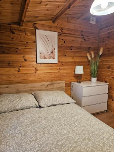 a bedroom with a bed and wooden walls at Domki w lasku in Wiele