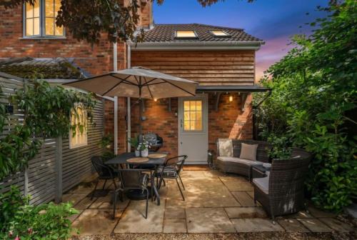 a patio with a table and chairs and an umbrella at Beautiful New Forest Hideaway in West Wellow