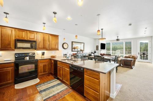 a large kitchen with wooden cabinets and a living room at Riverside Condo - Gorgeous Spokane River View in Post Falls