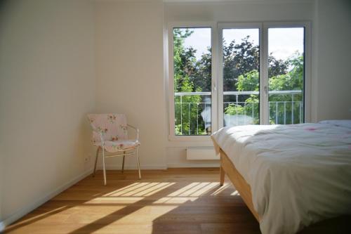 a bedroom with a bed and a chair and a window at City Lake & Peaks Thun in Thun