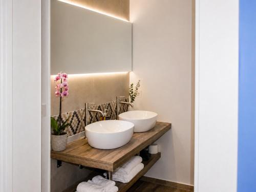 two sinks on a wooden shelf in a bathroom at Astra - Exclusive Rooms in Castelsardo