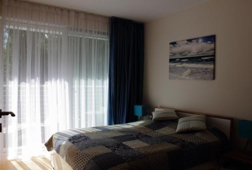 a bedroom with a bed and a large window at Apartament Flotylla Międzyzdroje in Międzyzdroje