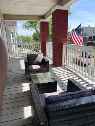 a porch with wicker furniture and an american flag at Modern Niagara Loft with Private Sunset Balcony Duplex in Niagara Falls