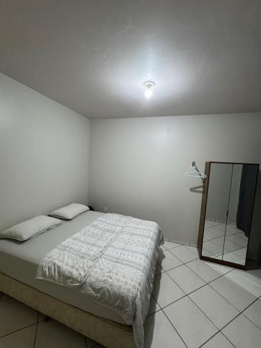 a white bedroom with a bed and a mirror at Lindo Apto102 em Primavera do Leste in Primavera do Leste