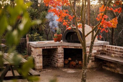 a brick fireplace with a pizza oven in a garden at Harvest Cottage Blue Mountains in Leura