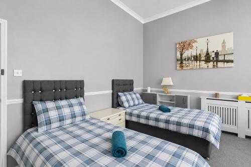 two beds with blue pillows in a room at Spacious two bedroom flat in Lansdowne in Bournemouth