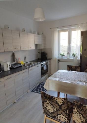 a kitchen with white cabinets and a table with chairs at Dana in Sokołowsko