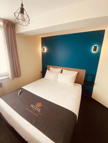 a large bed in a room with a blue wall at Hôtel les Paturelles in Avesnelles
