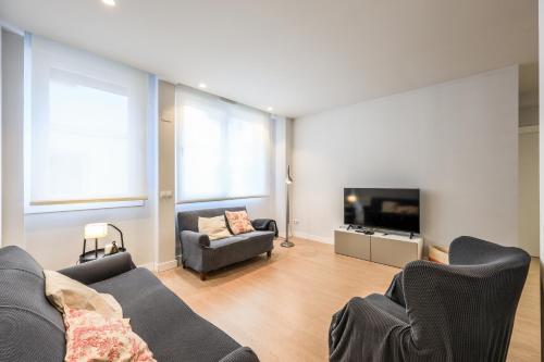 a living room with a couch and a tv at Spacious Home with Private Garden and Parking in Madrid