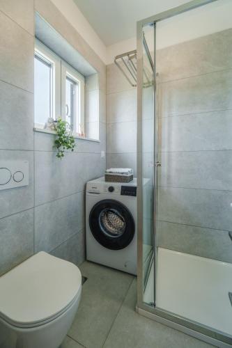 a bathroom with a toilet and a washing machine at Apartments Cvelic Milovcic in Malinska